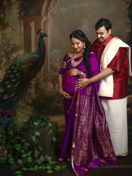 A couple portrait celebrating their journey to parenthood in a traditional South Indian style. The rich textures of their attire and the painterly backdrop add a layer of heritage and elegance.