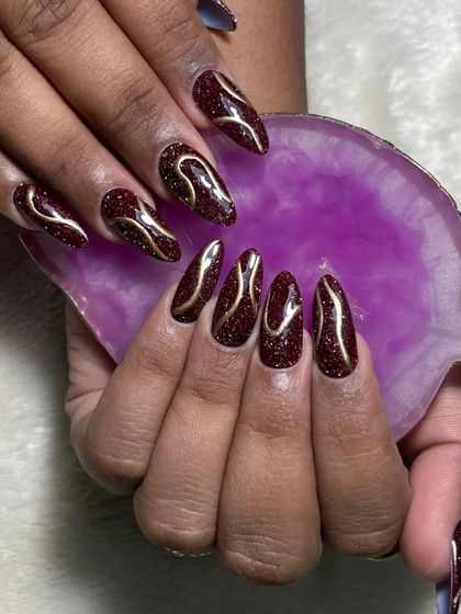 A glamorous design featuring deep red disco glitter polish with elegant gold line art. The sparkle and shine are perfect for a night out.