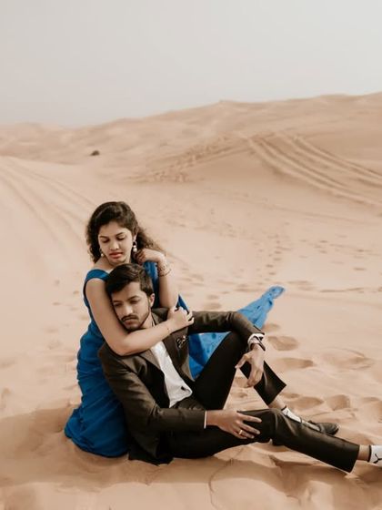 A romantic embrace in the desert, with the bride's blue dress creating a beautiful visual against the sand.