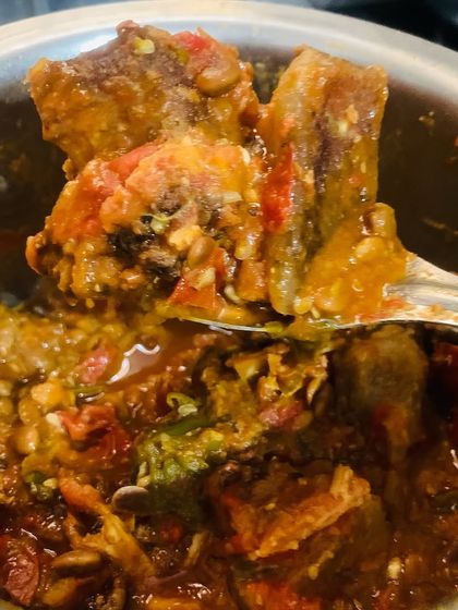 A perfect bite of smoked pork with Axone, showing the tender meat and thick gravy.