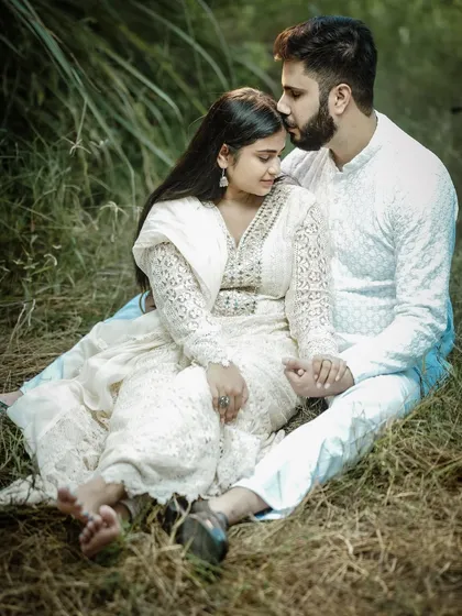 A tender forehead kiss captured during an outdoor pre-wedding session. The natural lighting and comfortable poses make for a genuine and heartfelt portrait.
