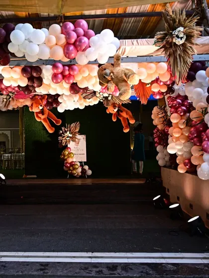 A grand entrance designed for a teddy bear-themed baby shower. The walkway is framed by a massive balloon arch in shades of pink, mauve, and white, with adorable teddy bears hanging from the structure to welcome guests.