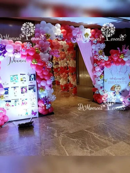 The entrance area for the winter-themed party, featuring a milestone photo board and a welcome sign, both framed with festive red, white, and gold balloon garlands.
