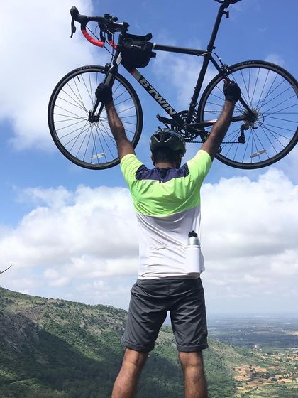 The ultimate Nandi Hills victory pose. A rider holding his Btwin bike high against a backdrop of hills and a beautiful blue sky.
