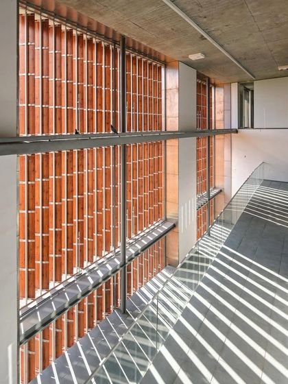 Afternoon light cascades across layers of ramps within the School of Public Policy at IIM Ahmedabad. The ramp system creates a continuous, accessible path through the building, fostering a sense of dynamic movement.