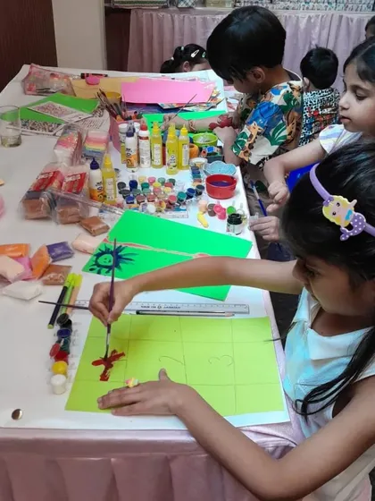 A close-up of the art and craft table, showing children deeply focused on their painting and crafting. I supply a wide variety of materials to spark their imagination.