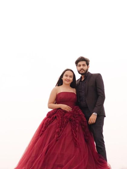 A full-length view of the gorgeous maroon ball gown against a clean, bright background. This minimalist approach really makes the couple and the detailed outfit pop.