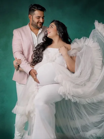 Creating a coordinated look for you and your partner is one of my favorite things to do. Here, my client wears a stunning white ruffled gown, perfectly complemented by a soft pink blazer for her partner, making their studio maternity session truly special.