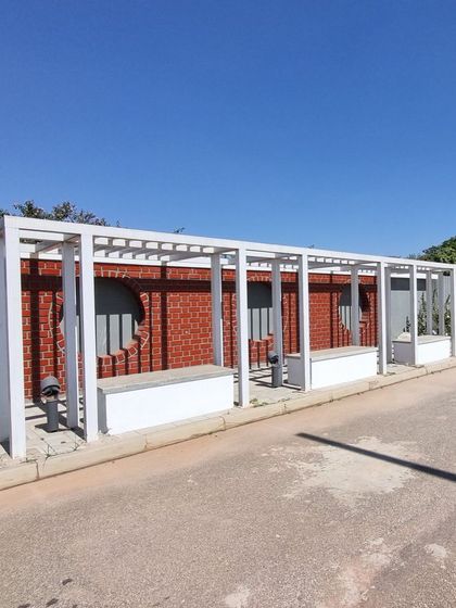 An angled view of the entrance walkway at Aamby City, showing the repetition of the pergola and seating modules.