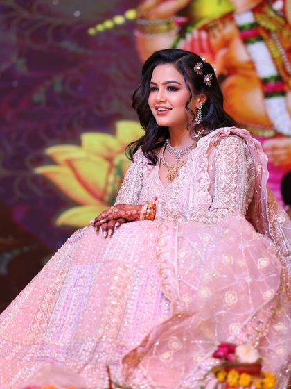 A stunning look for her engagement ceremony. The soft pink lehenga is complemented by glowing makeup and gentle waves in her hair, creating a romantic and elegant style.