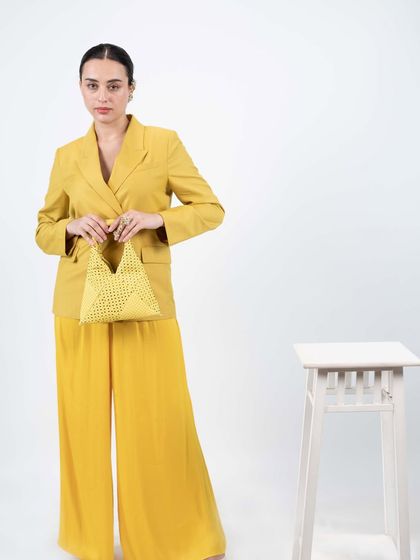 This butter yellow bag is perfect for the summer season. I designed it with a unique triangular shape, a comfortable ruched handle, and an all-over polka dot pattern made from tiny glass stones.