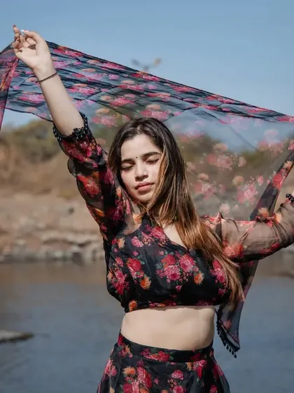 A beautiful outdoor shot with a floral lehenga. The model playing with her dupatta by the water creates a soft and romantic mood.