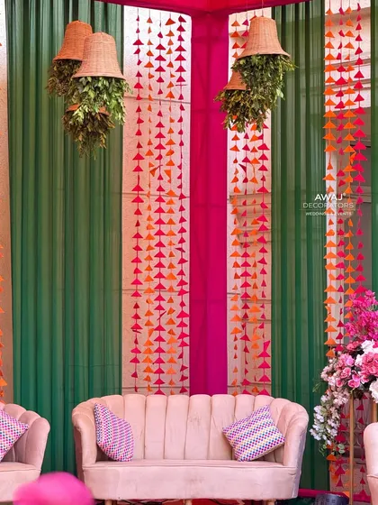 A close-up of the Mehendi stage seating, showing the hanging paper garlands and rustic planters that add a bohemian touch.