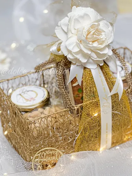 Another angle of the beautifully packed Diwali mesh basket hamper. The combination of the golden basket, white flower, and custom ribbon makes it a standout festive gift.