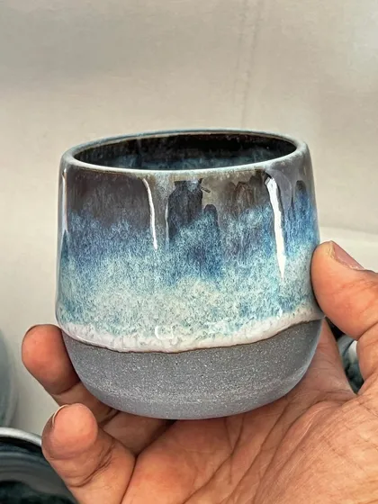 A close-up of a teacup, showing the rich, layered glaze that drips down the side.