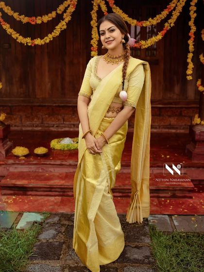 A full length shot of Anusree in a golden tissue kasavu saree. The drape is kept simple and elegant to highlight the texture and sheen of the fabric.