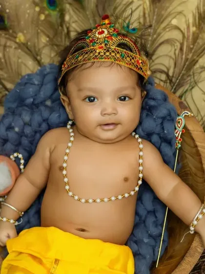 A beautiful portrait of a baby boy dressed as Bal Gopal for Janmashtami, complete with a crown and peacock feathers.