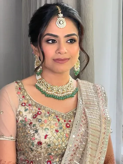 A close-up on the details. The neutral rose lips and softly defined eyes are the perfect complement to her pastel lehenga and emerald jewelry.