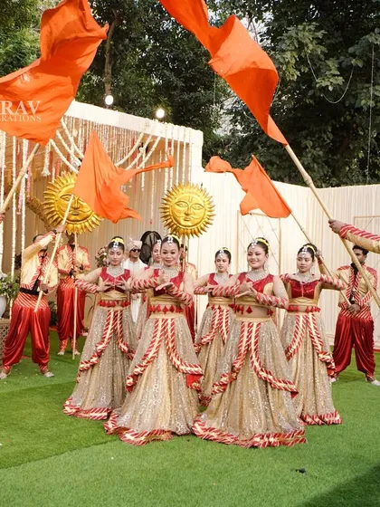 A powerful display of energy with dancers waving large saffron flags. This type of dynamic and colorful choreography is perfect for creating a high-energy, celebratory atmosphere for a groom's or couple's entry.