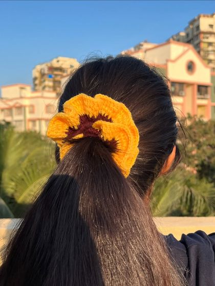 A sunflower-themed scrunchie in a ponytail. It's a fun and sunny accessory to brighten up your day.