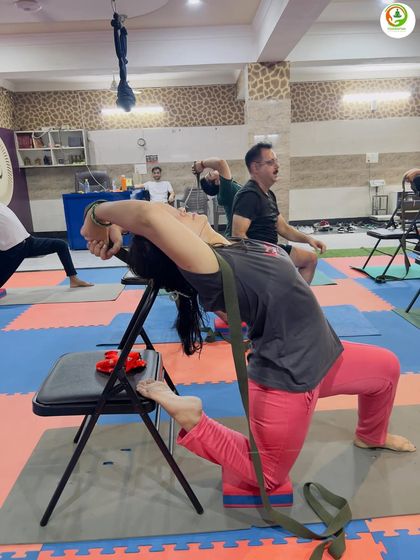 A yoga belt and chair are excellent tools for opening the shoulders and chest. This supported backbend helps improve posture and release tension from sitting at a desk all day.