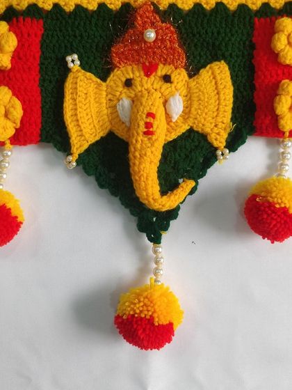 A close up of a single Ganpati motif, showing the detailed stitch work on the face, trunk, and the decorative pom-pom hanging below.