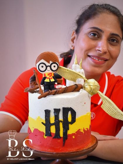 A student beaming with pride next to her magical Harry Potter themed buttercream cake.