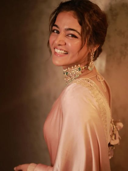 A joyful, smiling portrait of Wamiqa Gabbi. The soft satin drape complements her radiant expression.