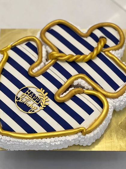 An anchor-themed cake with a nautical blue and white stripe pattern. The golden rope detail adds a touch of class. This is a great custom design for someone who loves the sea.