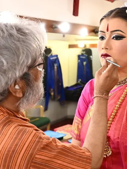 The final touches. A makeup artist carefully prepares my student Stuti Mukherjee for her arangetram. This pre-performance ritual is a quiet, focused time of transformation.