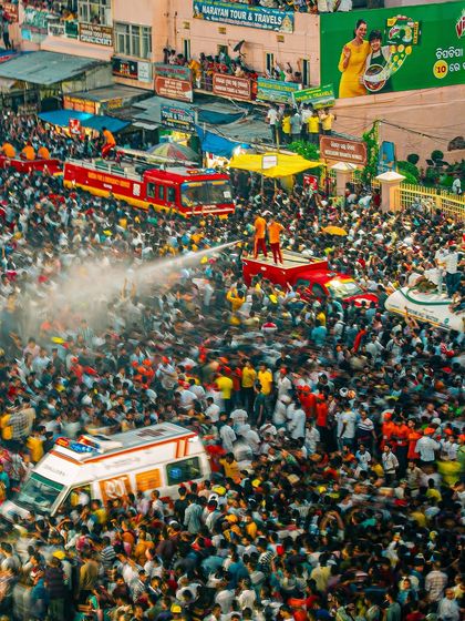 A fire truck sprays water on the crowds at the Rath Yatra to provide relief from the heat. An aerial shot showing the scale of both the crowd and the management efforts.