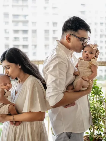 A tender moment between parents and their twins. The simple act of each parent kissing their baby's head creates a powerful and emotional family photograph.