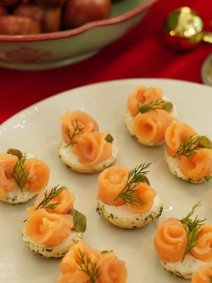 Smoked salmon and dill cream cheese blinis, elegantly presented for a Christmas event. These bite-sized treats are a classic choice for festive celebrations and cocktail parties.