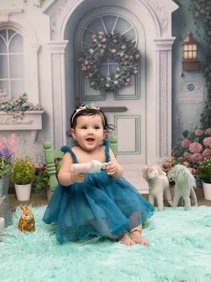 A storybook setting for a little princess. Her joyful expression is perfectly framed by our enchanting fairytale house backdrop, filled with flowers and whimsical details.