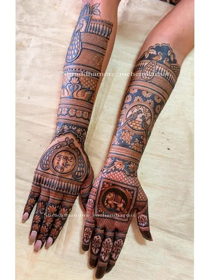 This design is filled with beloved traditional figures. It includes love birds, elephants, and peacocks, with the couple's initials 'S' and 'S' taking center stage on one palm.