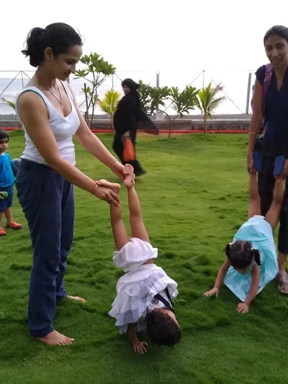 Children and parents playing together on the lush lawn. The success of a public space is measured by its use, and the immediate, joyful adoption of this park by the community is a testament to the project's impact.