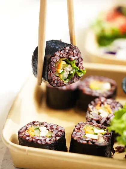 Capturing the fresh, clean appeal of healthy food is a specialty. This shot of black rice sushi uses bright, natural lighting and a simple composition to highlight the dish's healthy ingredients and modern aesthetic.