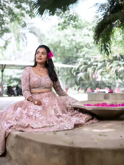 A wide shot of the model in a beautiful garden setting. The natural environment complements her soft and romantic look.