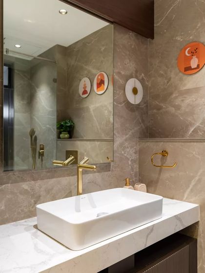 A harmonious blend of sophistication and warmth, this luxe bathroom features sleek marble walls, a custom white quartz countertop, and elegant gold fixtures that exude opulence. Curated wall art and soft, ambient lighting complete the refined experience.