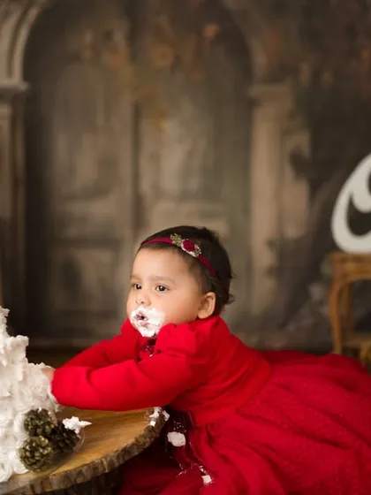 Let them eat cake! A first birthday cake smash is pure, messy, joyful chaos. This little one in her beautiful red dress didn't hesitate to dive right in, creating the most adorable memories of her big day.