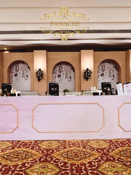 The elegant bar setup, with a pastel pink front and a backdrop of floral-printed arches.