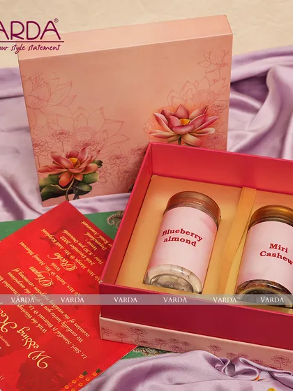 This elegant gift box features a delicate lotus theme on a soft pink background. Inside, it holds two jars of gourmet treats like Blueberry Almond and Miri Cashew, combining beautiful design with delicious flavors for your guests.