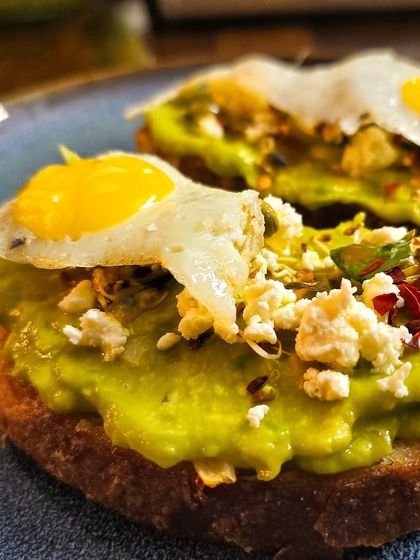Avocado toast topped with a perfectly fried quail egg. The small eggs are a perfect match for the toast.