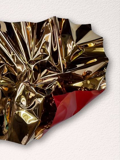 A detail of a gold and red Meteor piece, showing the brilliant red revealed beneath a fold of the crumpled gold steel.