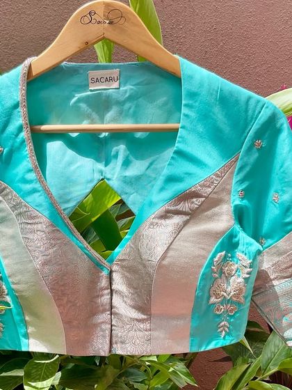 A patchwork blouse in subtle hues of turquoise and silver, featuring minimal floral embroidery for an understated yet elegant look.