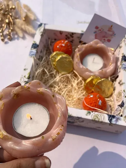 A cute and simple Diwali gift box with two floral resin tea light holders and chocolates.