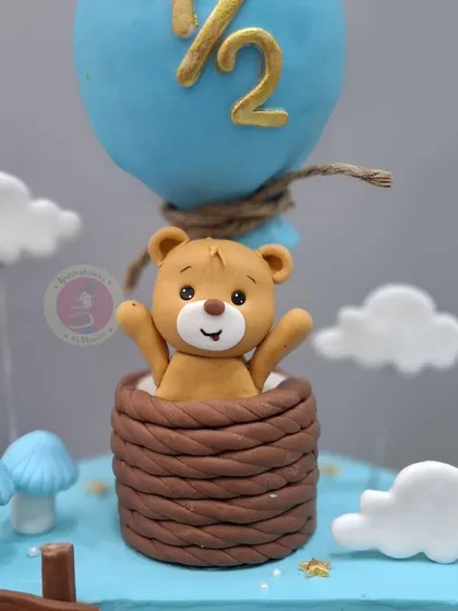 A close-up of the adorable teddy bear figurine peeking out of the hot air balloon basket.