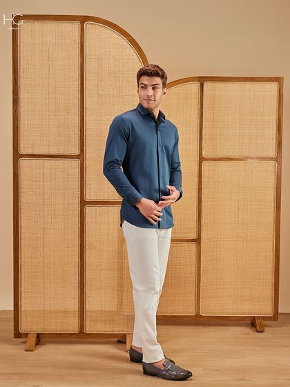 A full-length view of the teal shirt and white trousers. The color combination is fresh and sophisticated, suitable for a variety of occasions.
