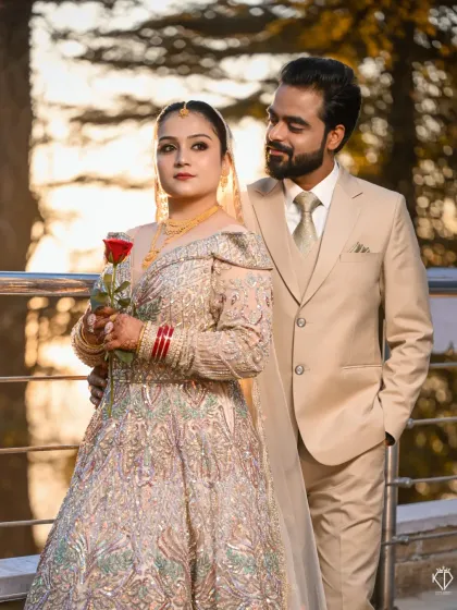 The groom looks lovingly at his bride, who holds a rose. This candid moment during a posed session captures the genuine affection between them, enhanced by the mountain sunset.