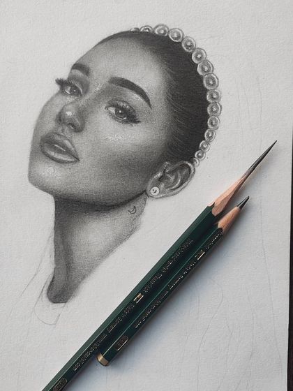 A work-in-progress shot of my first Ariana Grande graphite portrait. The face is fully rendered, showing the smooth skin texture before the hair is drawn.